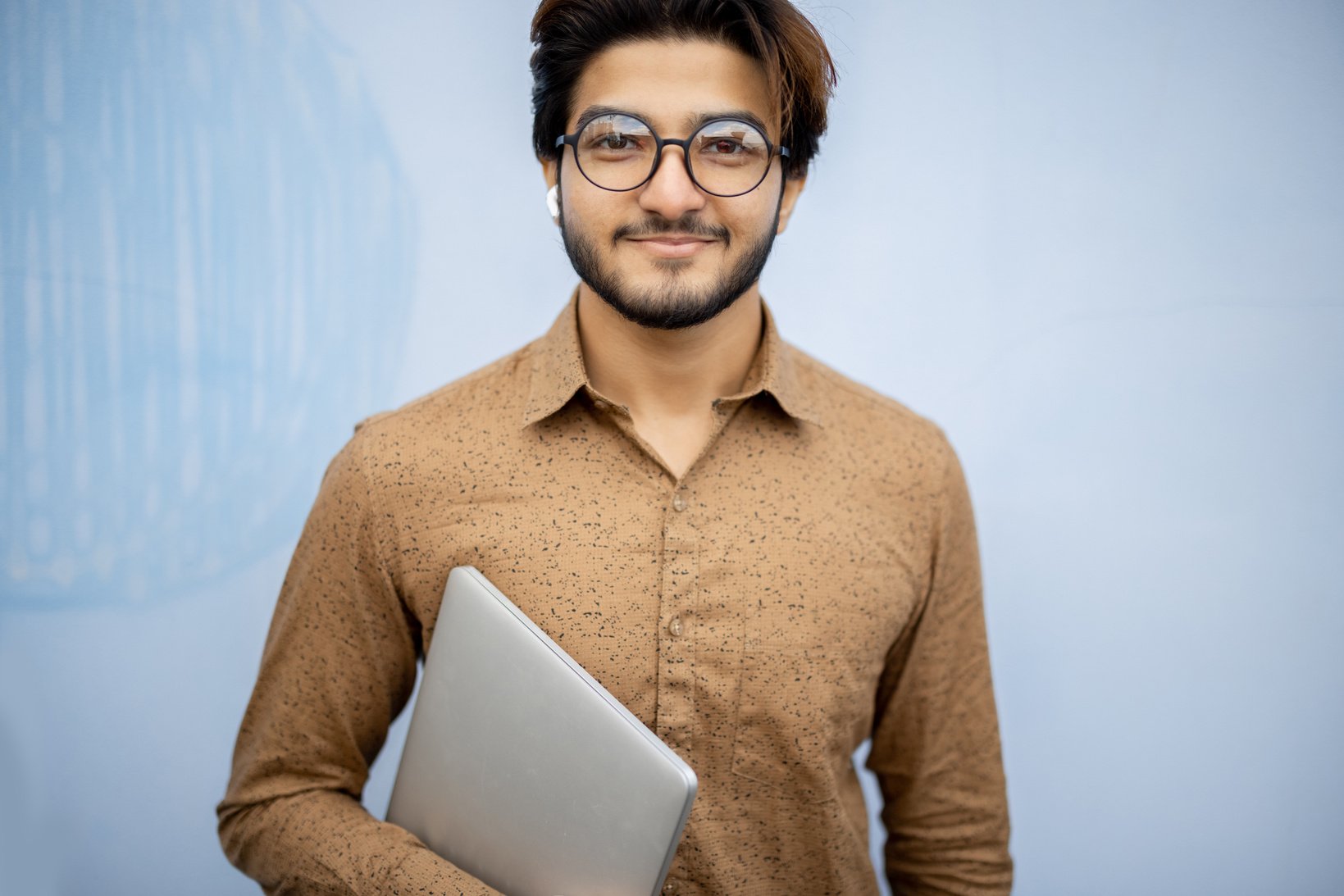 Young Indian Man with Laptop Looking at Camera